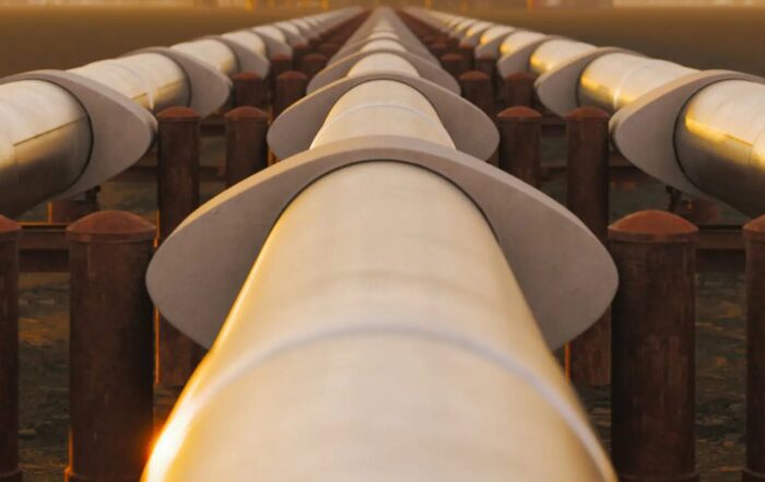 Pipelines leading to oil and gas facility at sunset, symbolizing energy infrastructure.