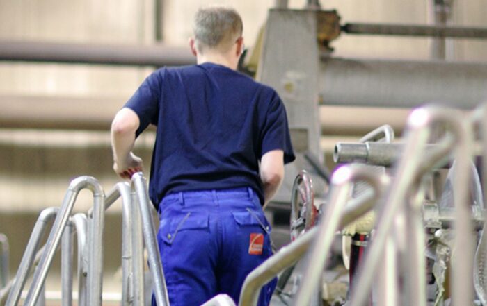 Maintenance technician walking up industrial equipment stairs inside a production facility.