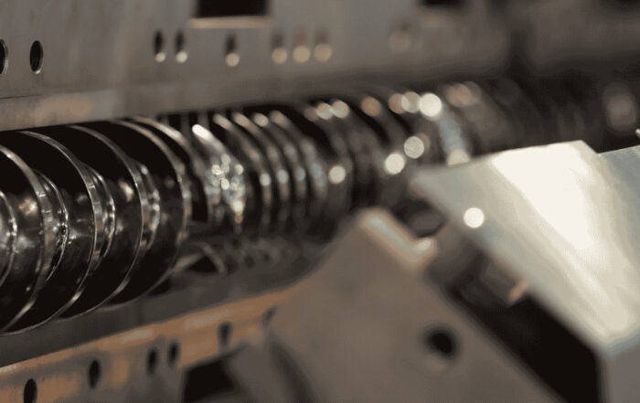 Close-up of a shiny industrial screw conveyor inside manufacturing equipment