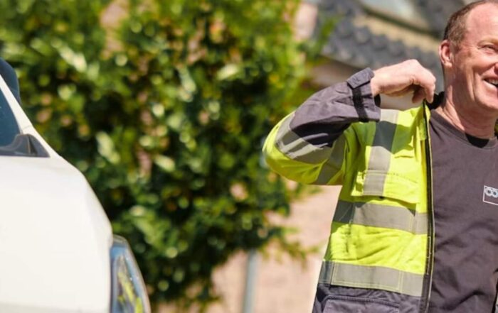 Cogas worker in a high-visibility jacket smiling next to a company van with the Cogas logo.