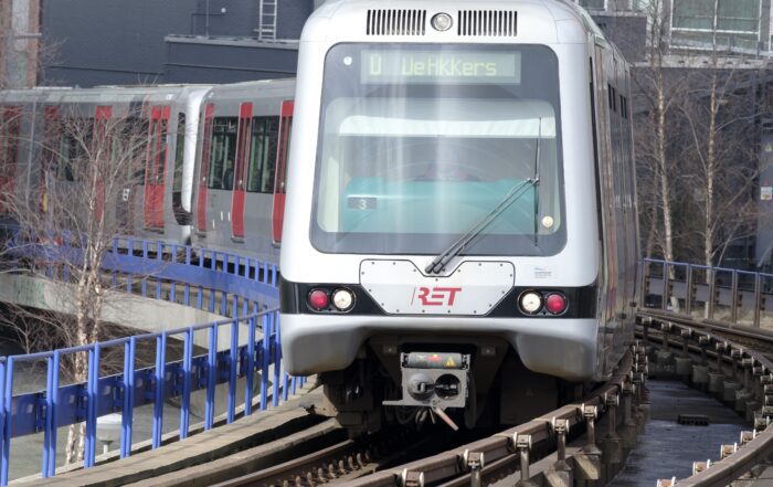 RET metro train on elevated curved tracks in an urban area.