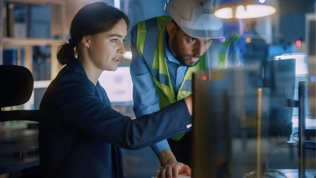 Engineer and technician reviewing equipment data together on a control room screen.