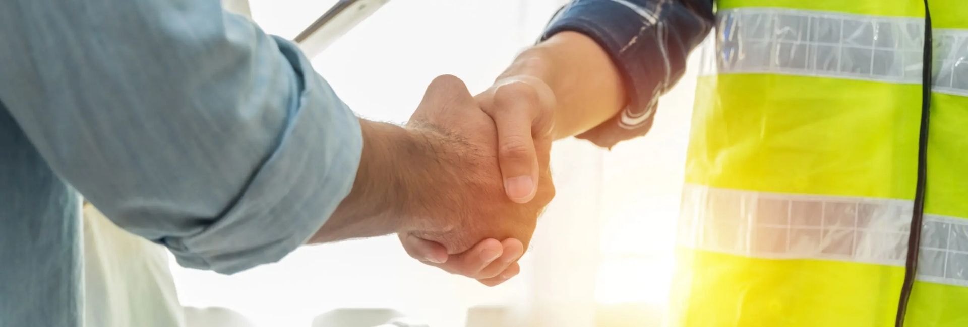 Engineer and client shaking hands at a worksite, symbolizing partnership
