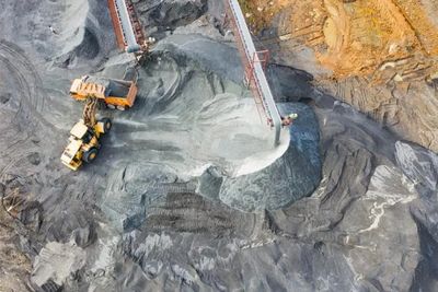 Aerial view of mining site with heavy machinery moving gravel and minerals.
