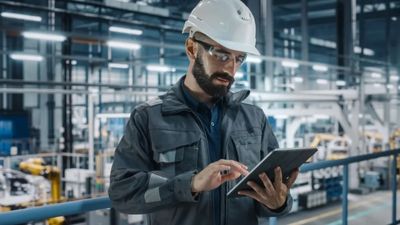 Engineer in a factory using a tablet for maintenance monitoring.