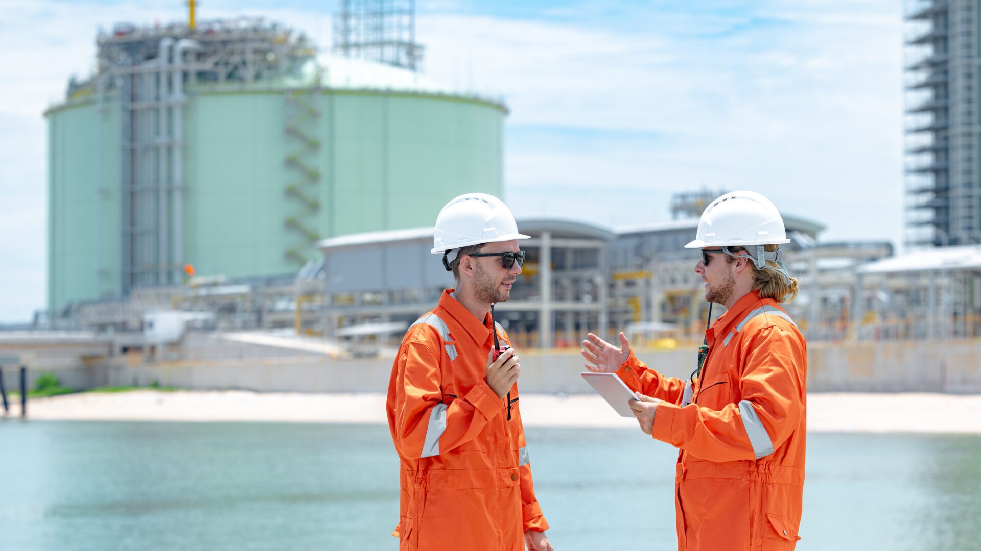 Two safety‑clad workers discussing work at an industrial facility